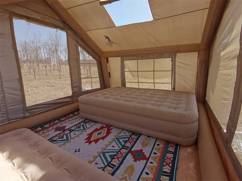 Furnished interior of a nine square metre inflatable tent with a bed and roof opening