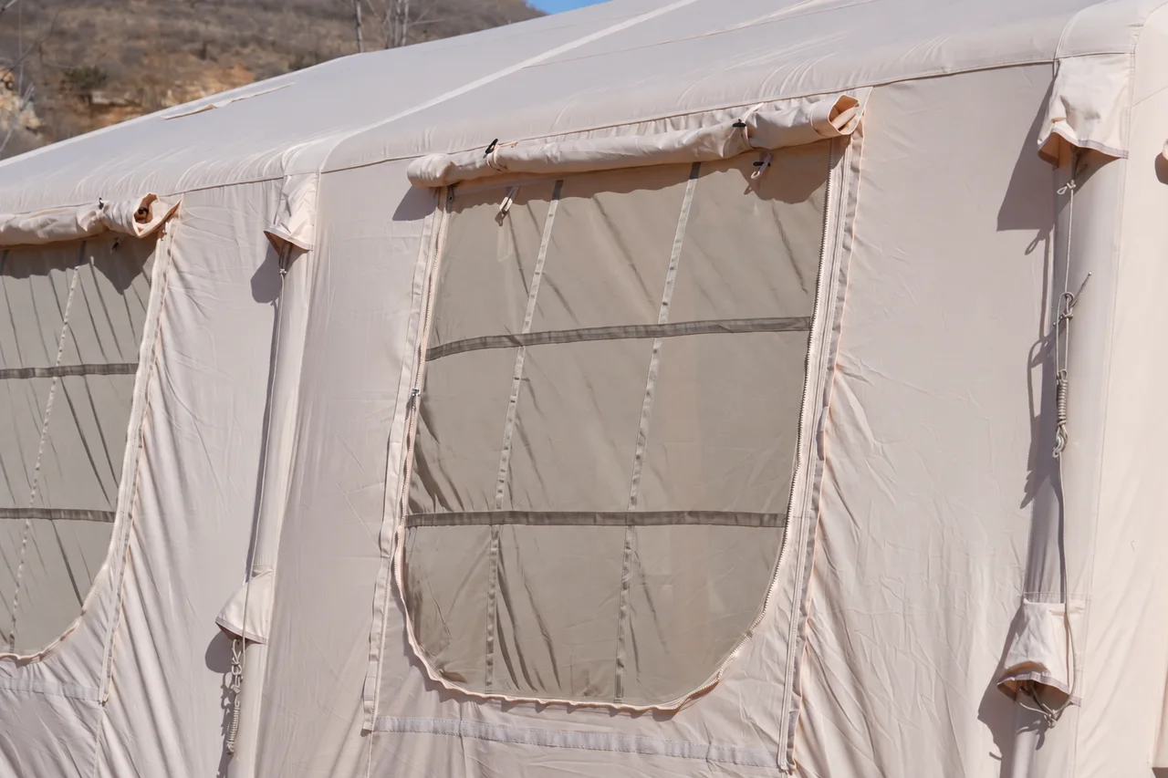Mesh window, zipper and rolled cover on a large beige inflatable glamping lodge
